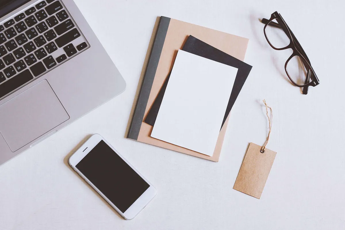 A desk with laptop, notebook and phone